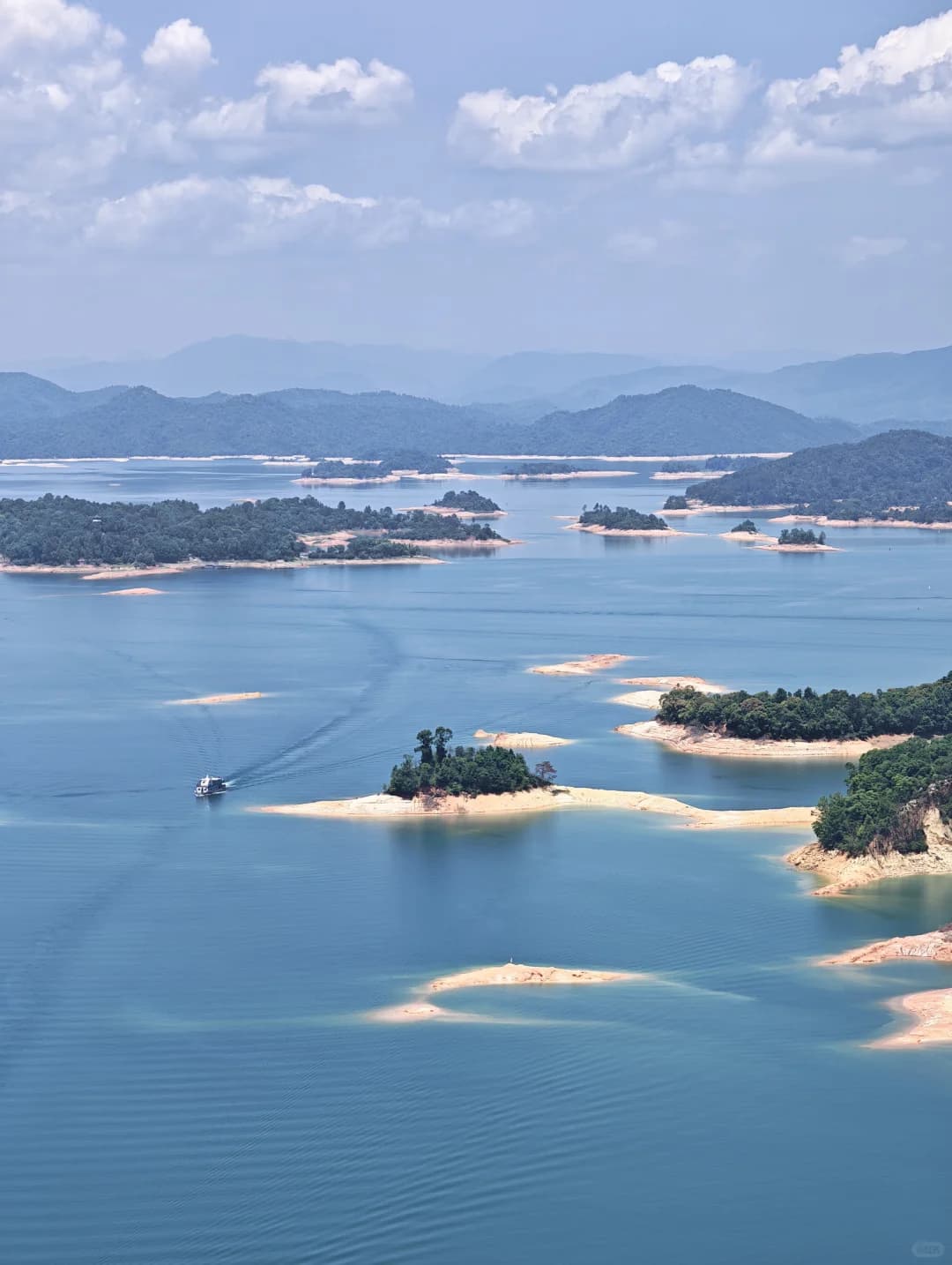 Forested islands, boats and blue water at Wanlü Lake in Heyuan