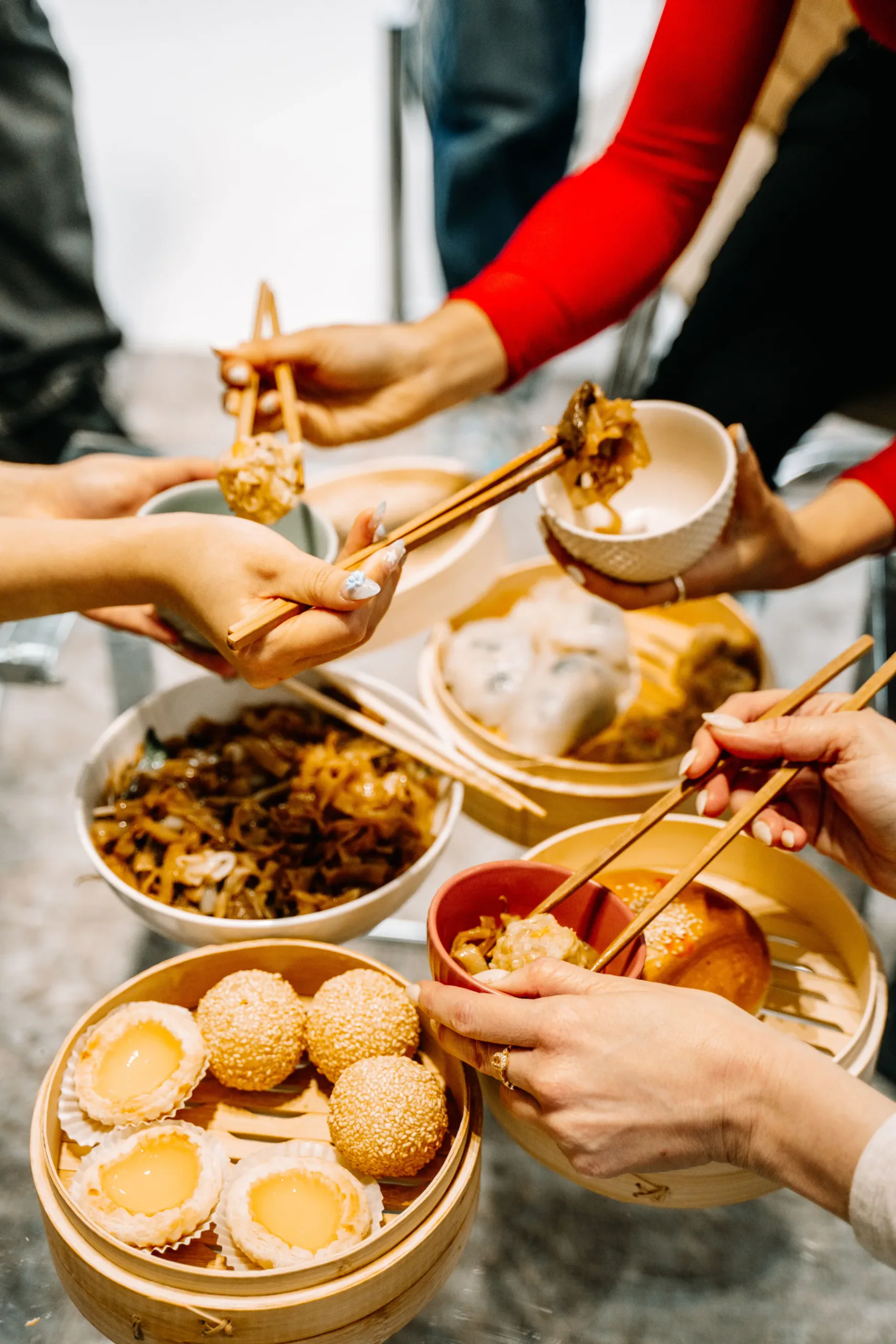 A tall view of diners reaching across a morning dim sum table