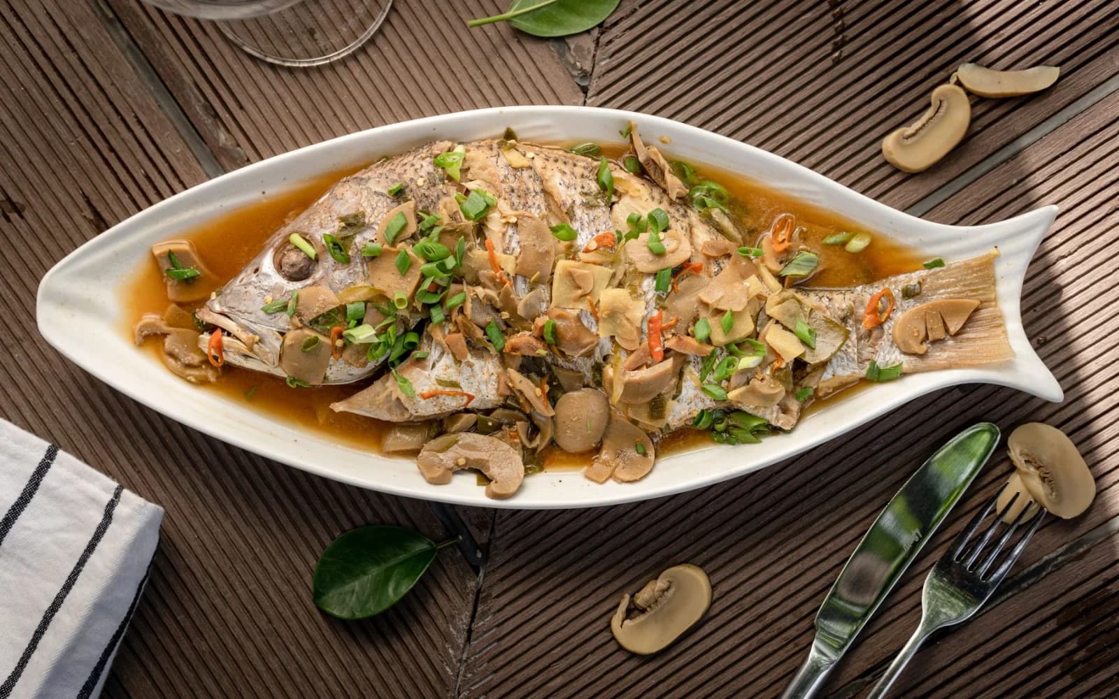 A whole steamed fish served with mushrooms and spring onion