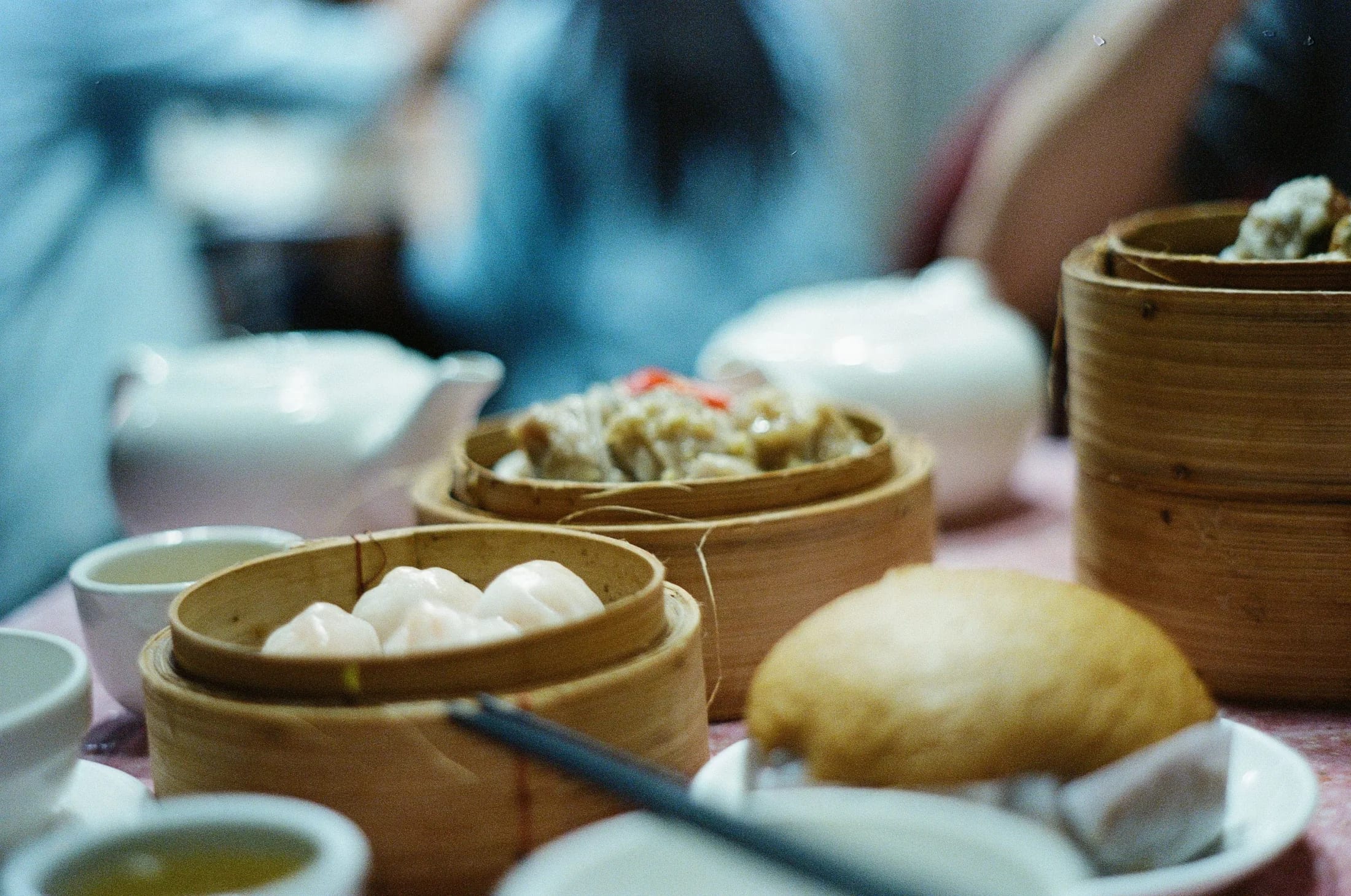 A yum cha table with teapots, cups and bamboo steamers