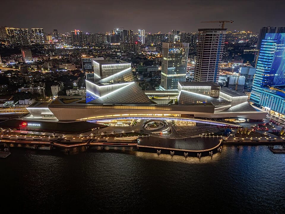 Aerial night view of Bai'etan Greater Bay Area Art Center beside the river