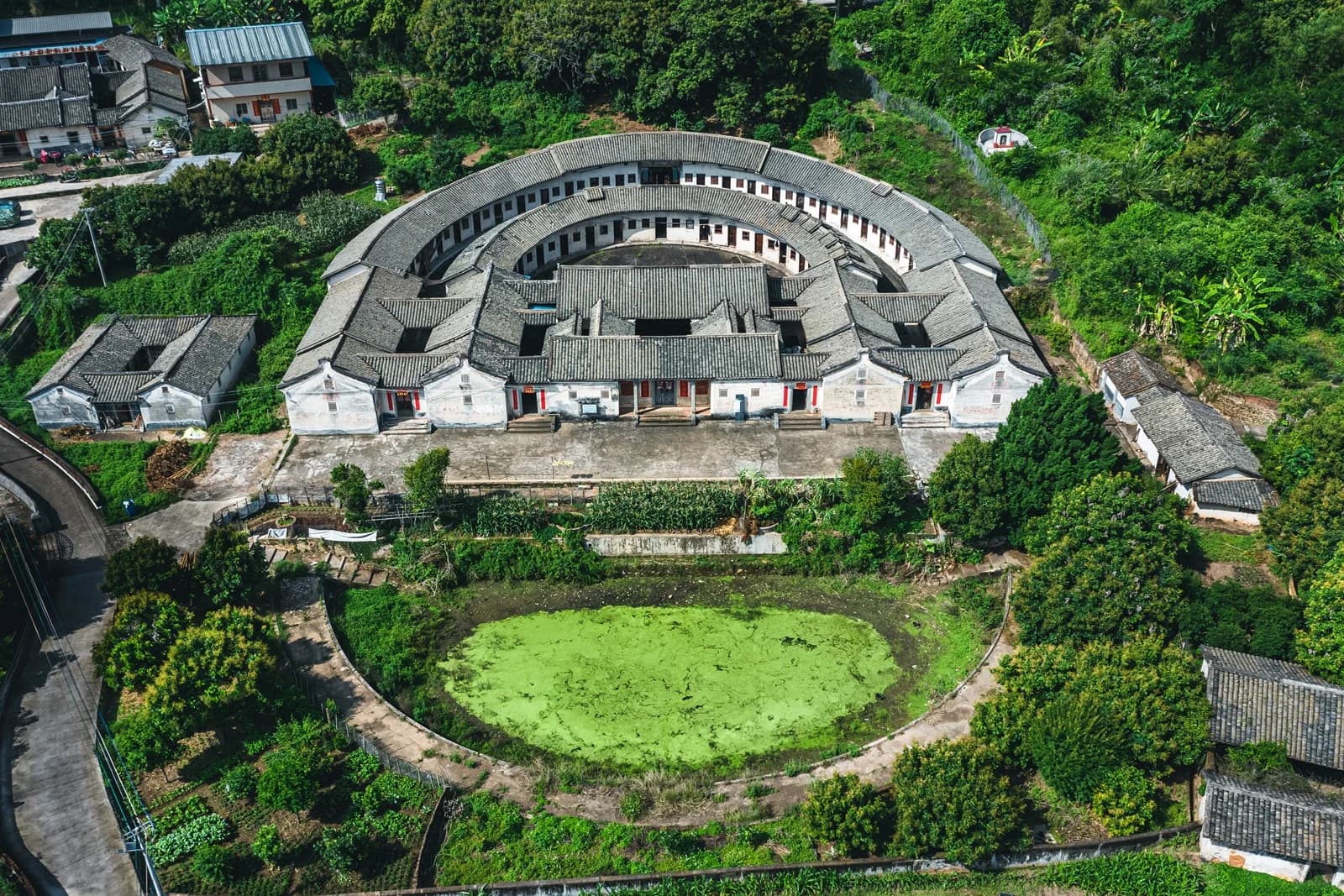 A semicircular Hakka walled house and its pond in Qiaoxiang Village, Meizhou