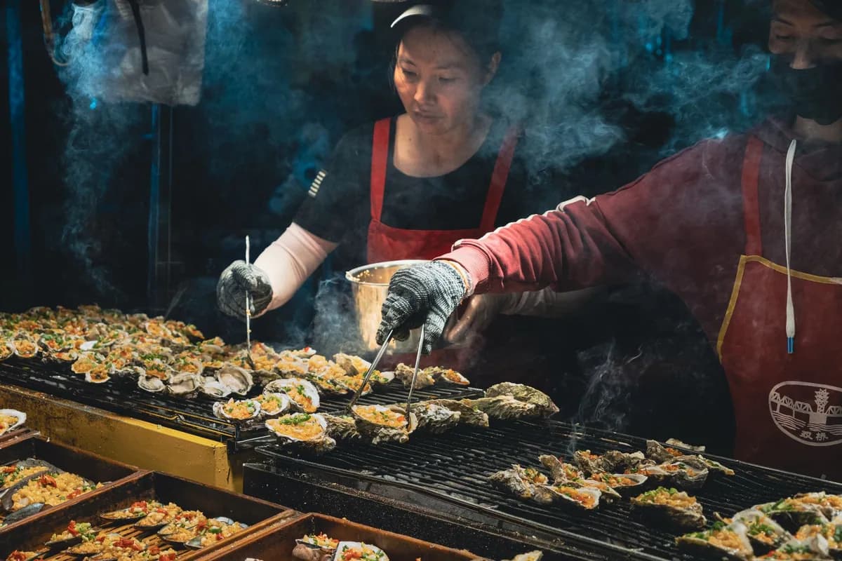 繁忙夜市攤檔上正在燒烤的調味生蠔
