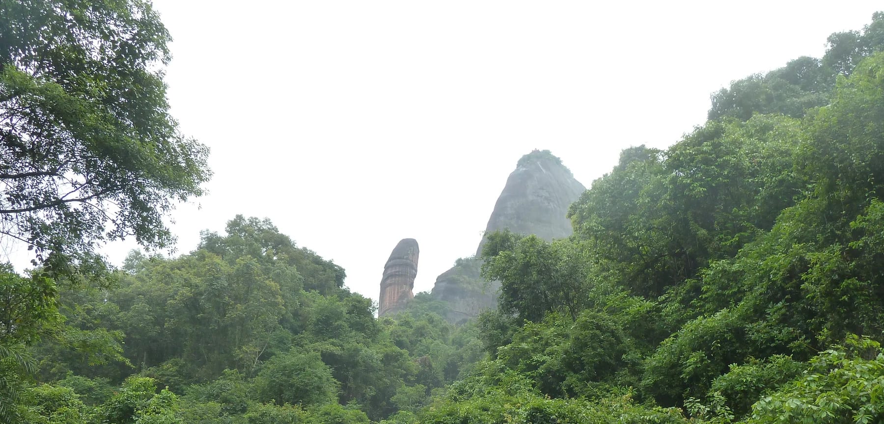Yangyuan Stone rising behind trees at Mount Danxia